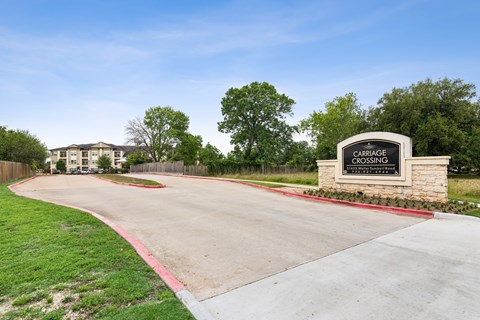 A sign that says "CARRIAGE CROSSING" stands in front of a building.