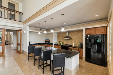 A kitchen with black chairs and a black fridge.