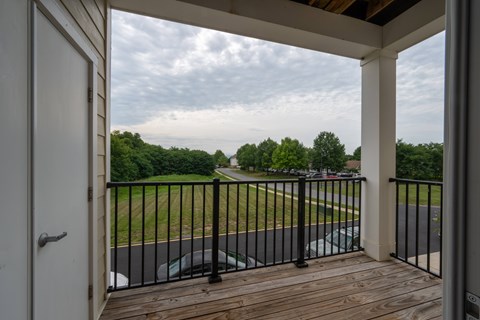 A view from a deck looking out to a parking lot and trees.