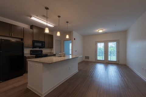 A kitchen with a black refrigerator and wooden floors.