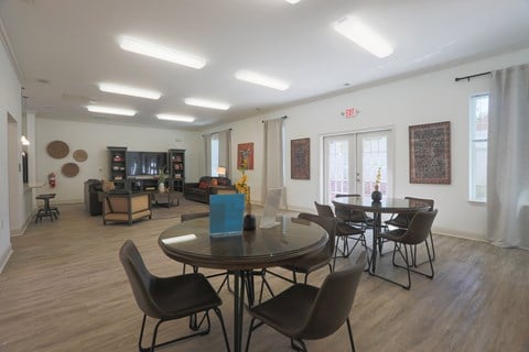 A room with a round table and chairs in the foreground and a living room in the background.