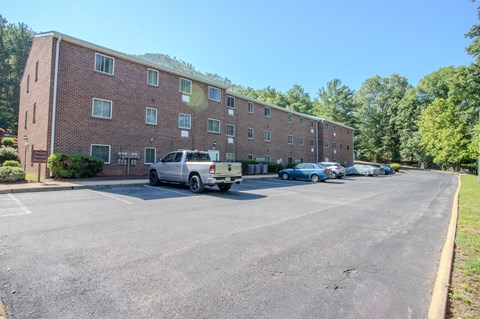 A parking lot in front of a brick apartment building.