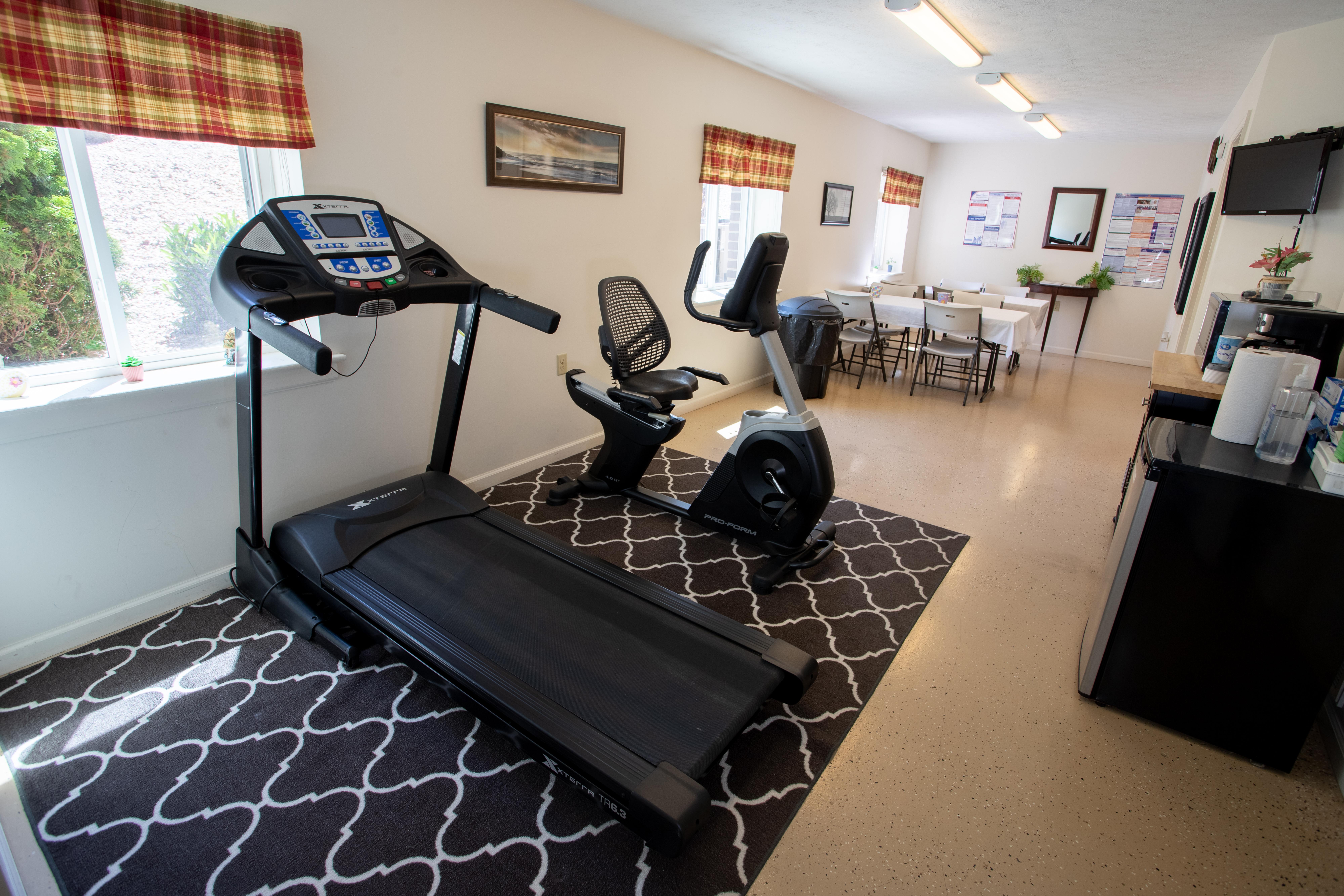 A treadmill and exercise bike in a room with a patterned carpet.