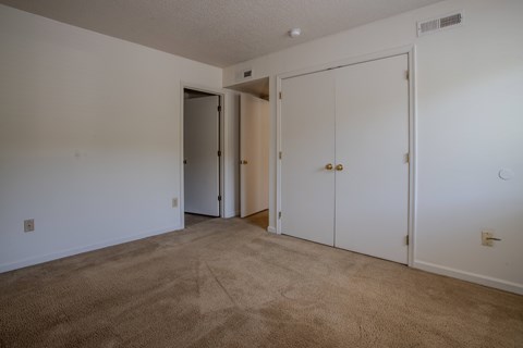 A room with carpeted floor and white walls with a door open to a hallway.