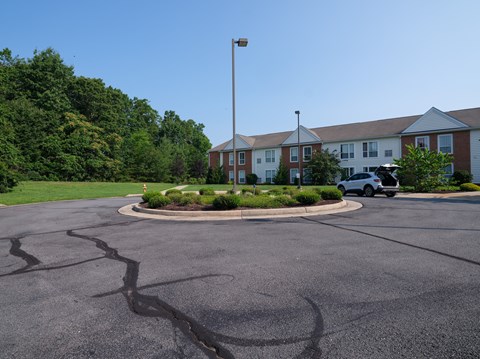 A parking lot with a white car and a building in the background.