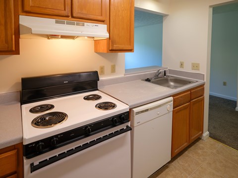 A kitchen with a white stove top oven and a white dishwasher.