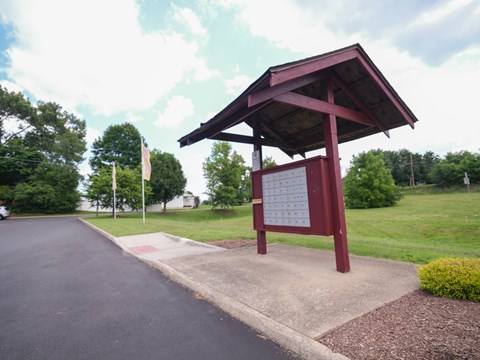 A red and white sign is on a stand in front of a road.