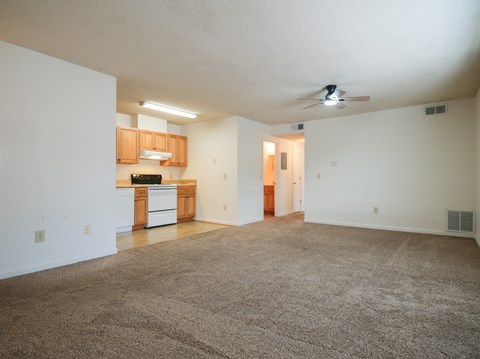 A spacious living room with a carpeted floor and a ceiling fan.
