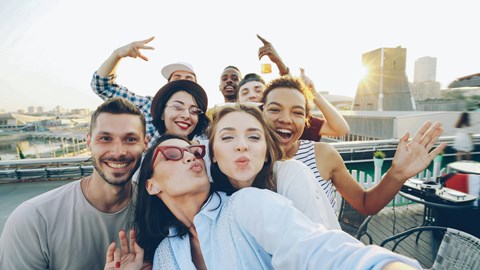 A group of friends are taking a selfie on a rooftop.