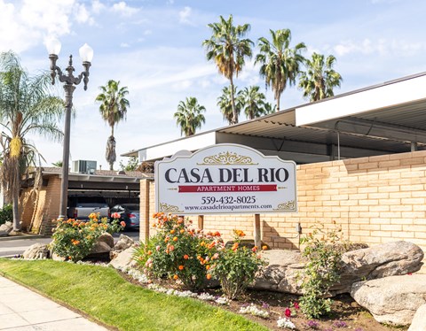 A sign for Casa Del Rio Apartment Homes is displayed in front of a building.