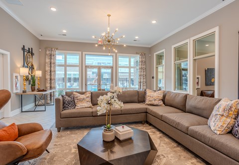 A living room with a large sectional sofa and a coffee table in front of a large window.