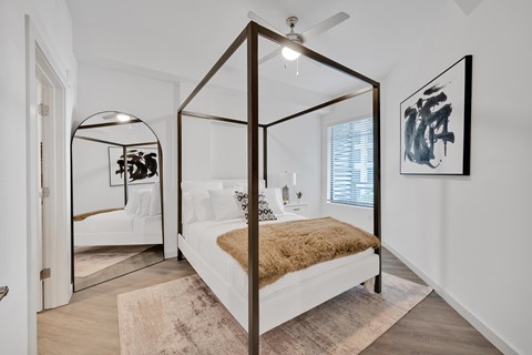 A bedroom with a four poster bed and a mirrored wall.