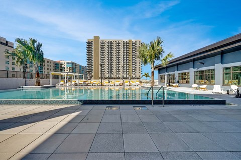 A large swimming pool surrounded by a tiled floor and palm trees.