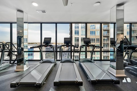 A gym with treadmills and a view of the city.