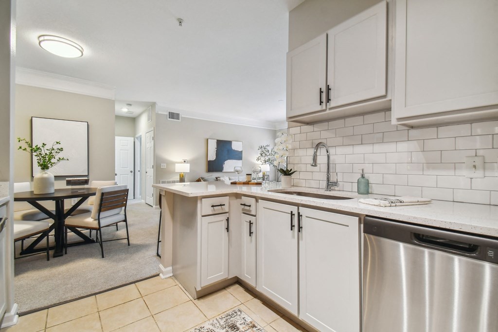 an open kitchen with white cabinets and a dining room with a table