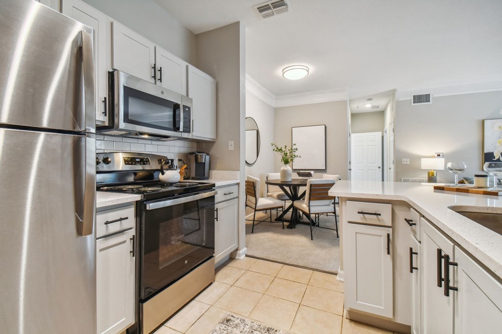 an open kitchen and dining room with stainless steel appliances and white cabinets