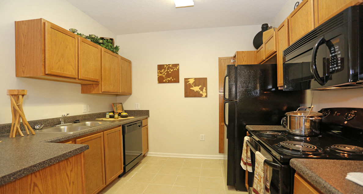 Charming kitchen with oak cabinetry and black appliances at The Columns at Bear Creek, New Port Richey, FL 34654