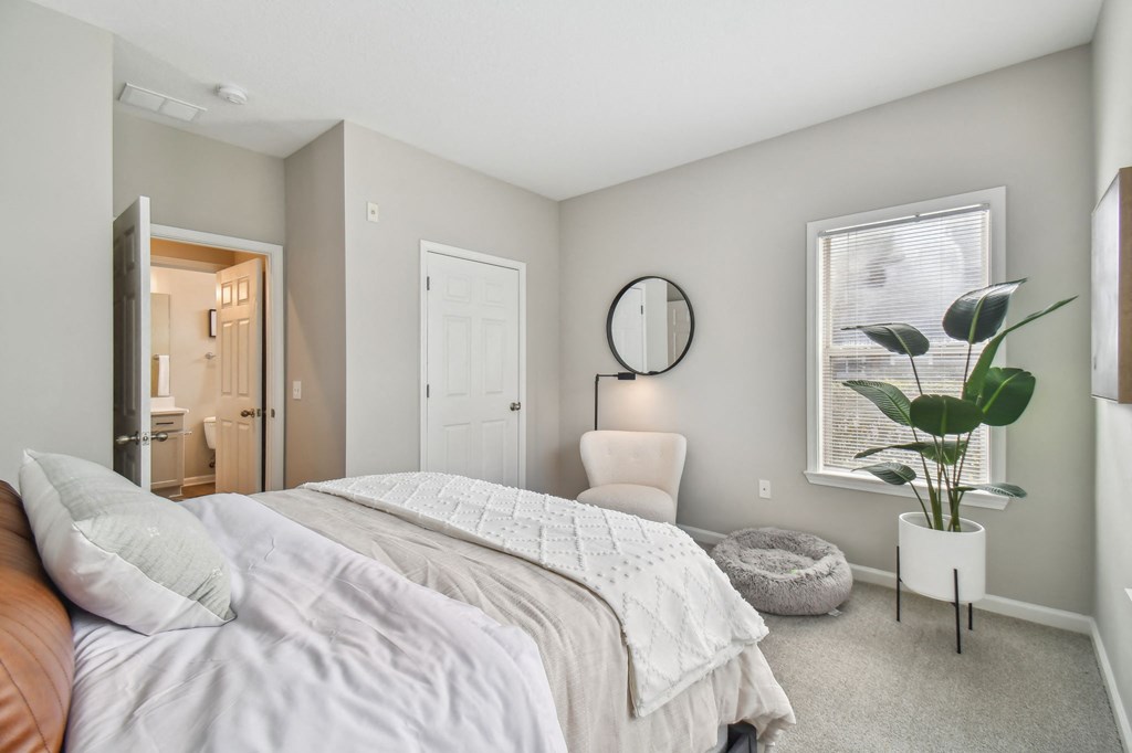 a bedroom with a bed and a chair and a window