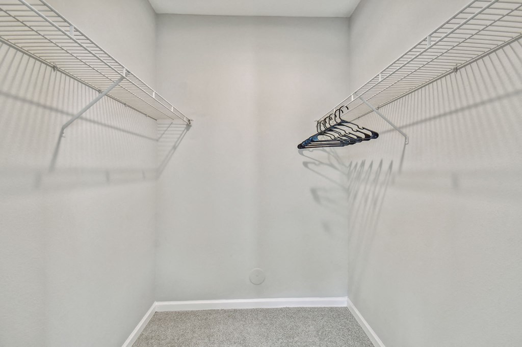 an empty closet with white walls and a mirrored closet door
