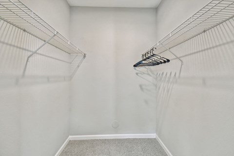 an empty closet with white walls and a mirrored closet door