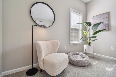 a living room with a chair and a mirror and a plant