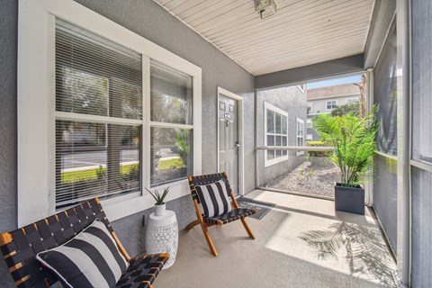 a porch with two chairs and large windows