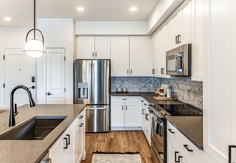 A modern kitchen with white cabinets and a stainless steel refrigerator.