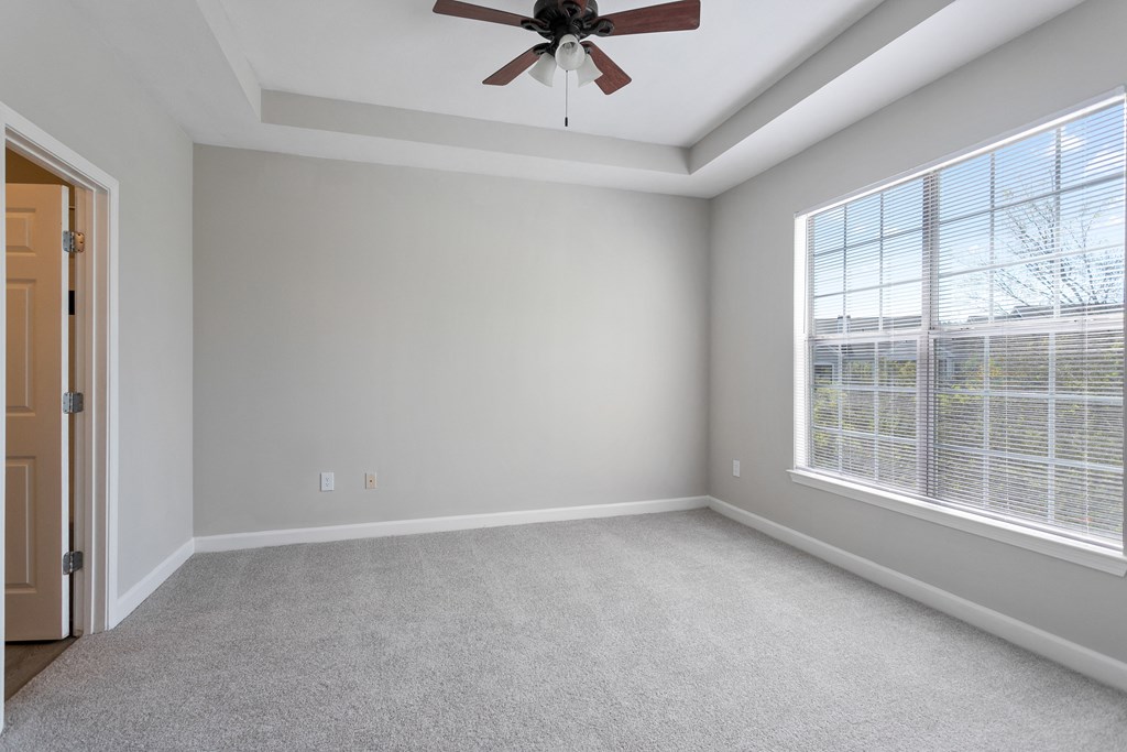 a bedroom with a large window and a ceiling fan