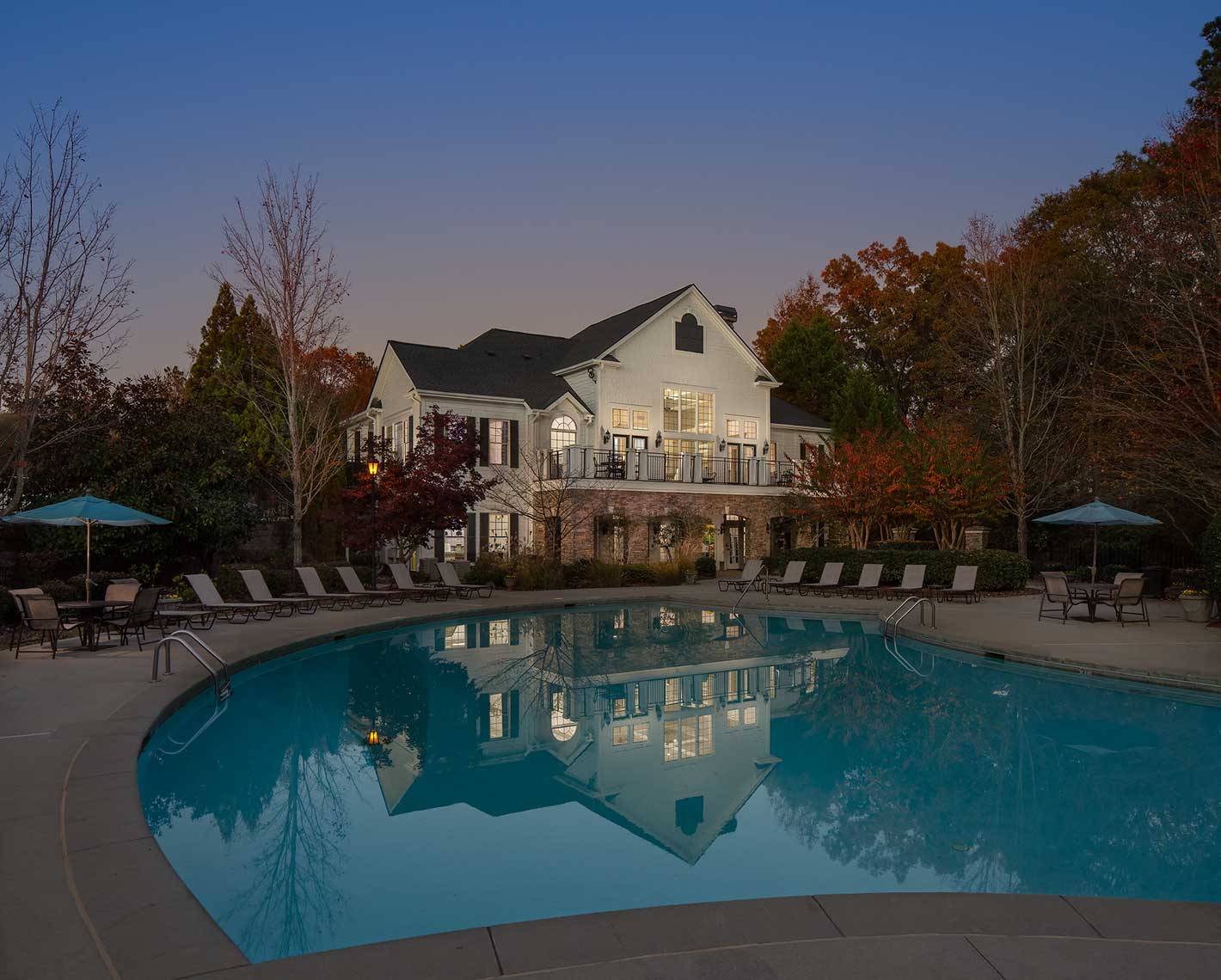 a pool at dusk with a large house in the background