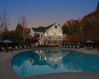 a pool at dusk with a large house in the background