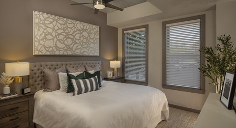 a bedroom with a large bed and two windows