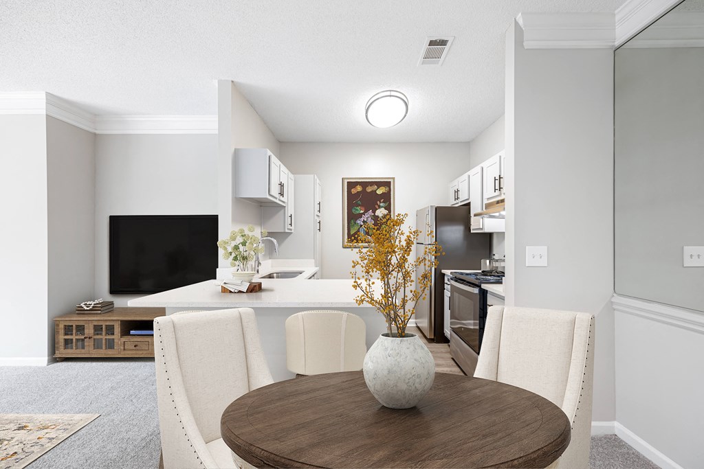 a dining area with a table and chairs and a kitchen in the background