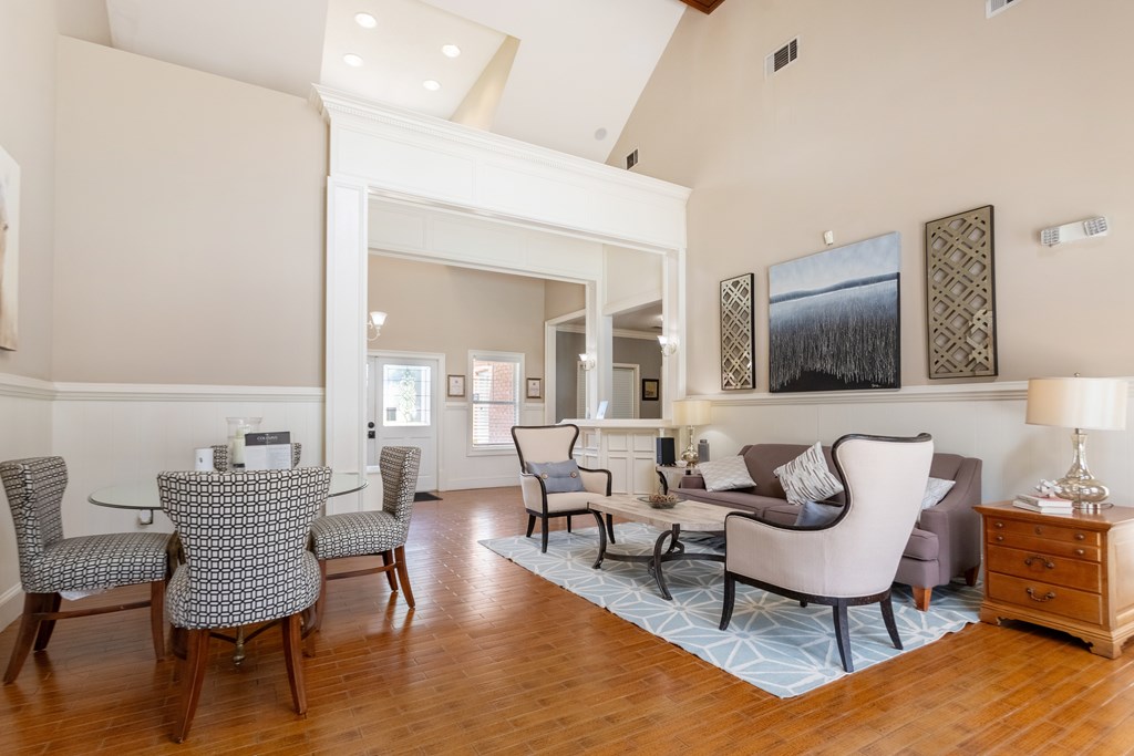 A living room with a grey sofa, a wooden table and chairs, and a painting on the wall.
