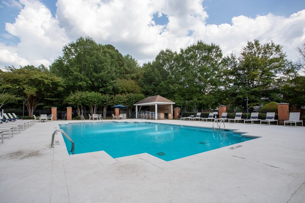 A large swimming pool surrounded by trees and lounge chairs.