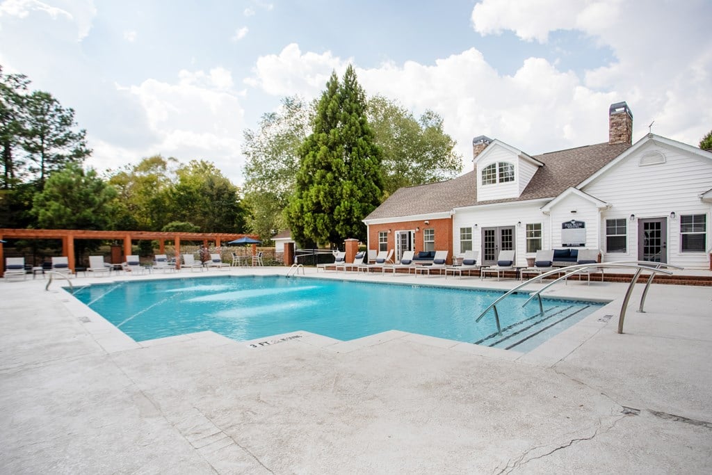 A large swimming pool in front of a white house.
