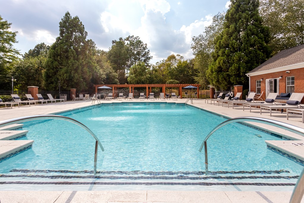 A large swimming pool surrounded by trees and a building.