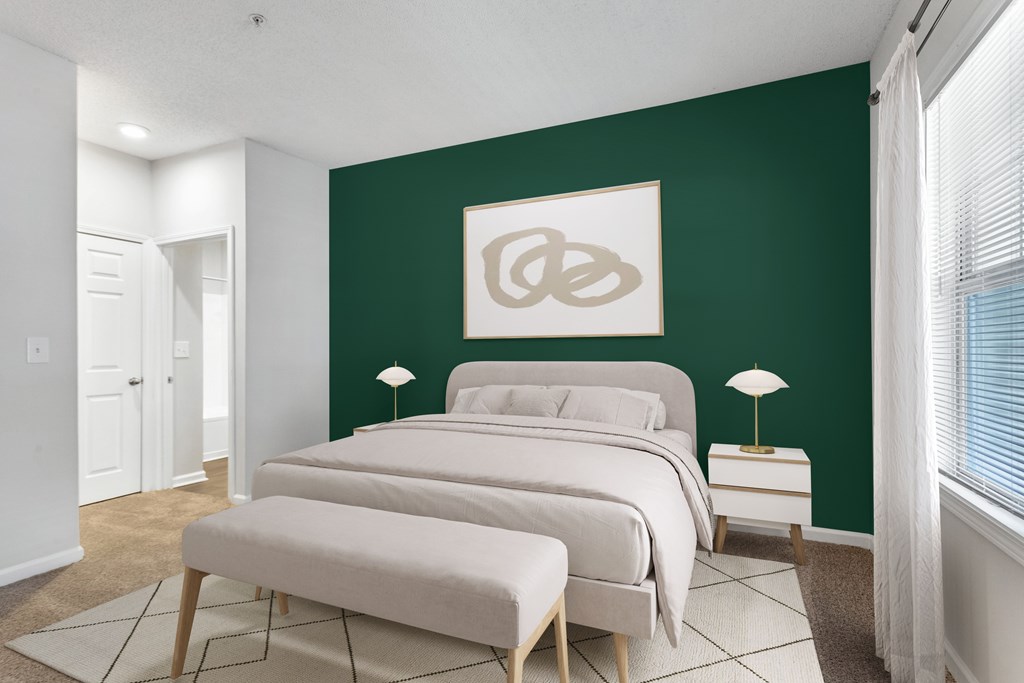 A bedroom with a green wall and a bed with a white headboard.