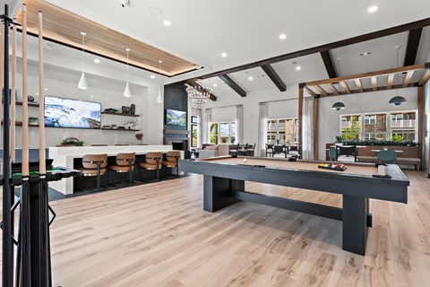 A modern living room with a long black table and wooden floors.