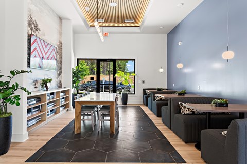 A modern living room with a dining table and chairs, a couch, and a potted plant.