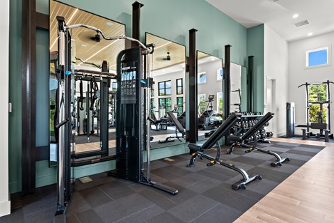 A gym with a variety of equipment including a squat rack, a leg press machine, and a bench press.