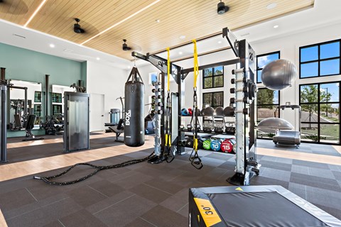 A gym with a punching bag, weights and exercise equipment.