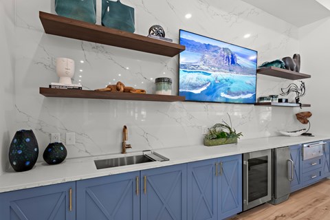 A modern kitchen with blue cabinets and a marble backsplash.