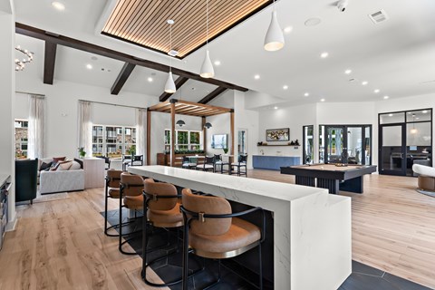 A modern living room with a long white table and brown chairs.