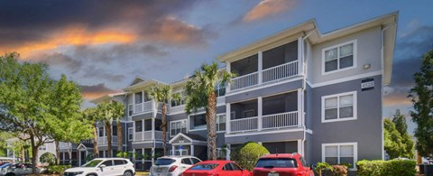 an image of an apartment complex with cars parked in front of it