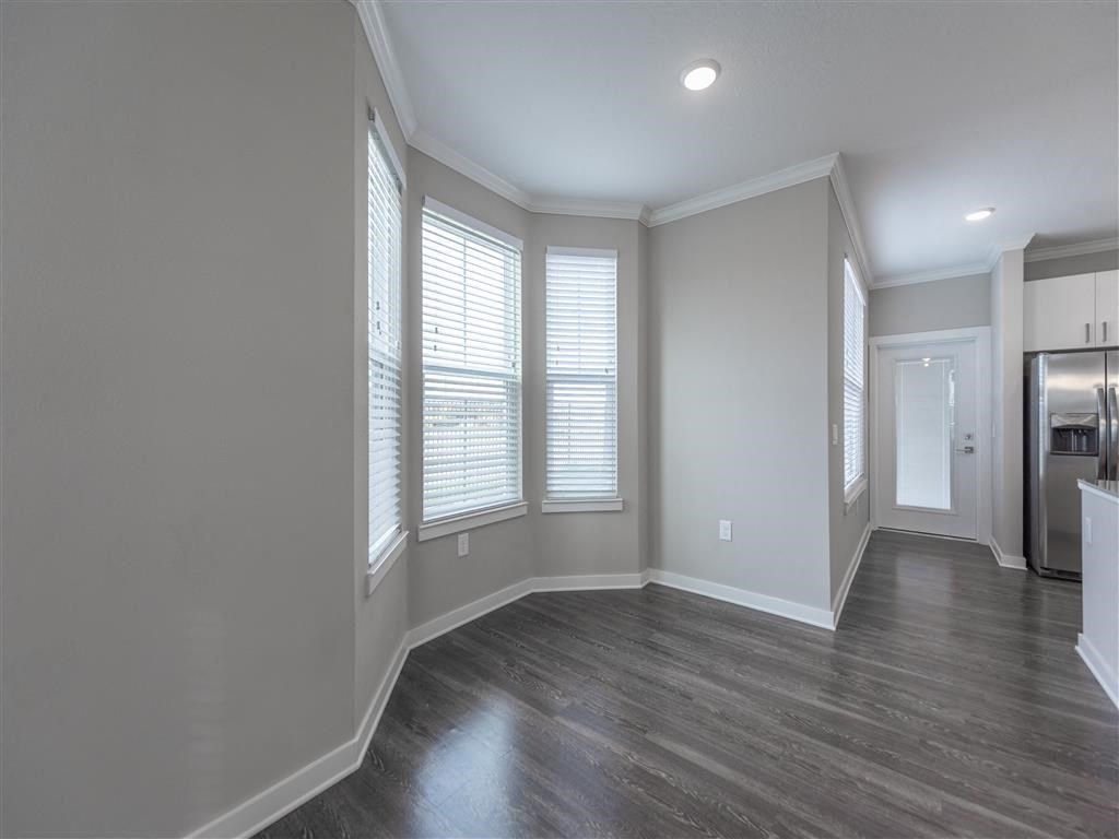 an empty room with three windows and a kitchen in the background at Verso Apartments, Davenport, FL, 33896