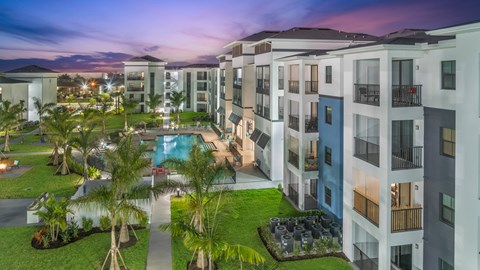 A modern apartment complex with a pool and palm trees.