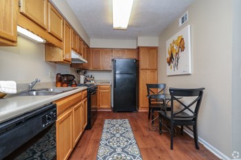 Fully equipped kitchen with oak cabinetry and black appliances Fully equipped kitchen with oak cabinetry and black appliances at The Columns at Lake Ridge, GA 30338 - Photo Gallery 3
