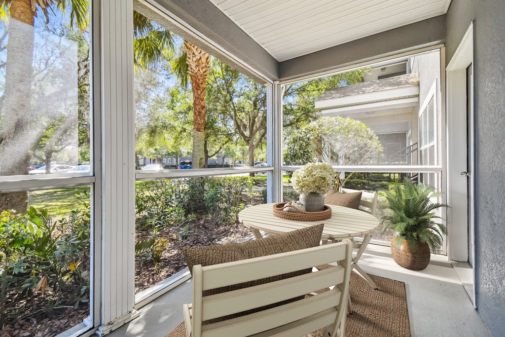 a screened in porch with a table and chairs