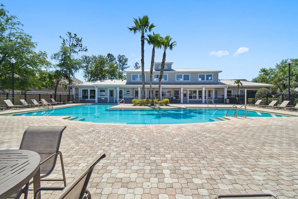 a resort style pool with chaise lounge chairs and a building in the background
