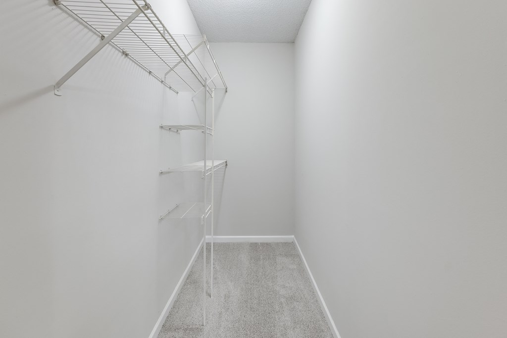 a walk in closet in a bedroom with gray walls and a white ceiling